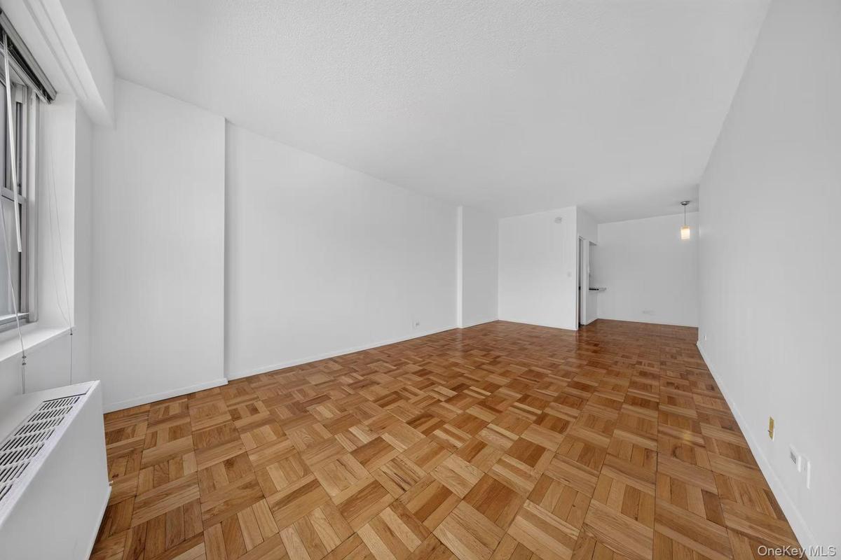 Expansive living space featuring parquet wood flooring and crisp white walls