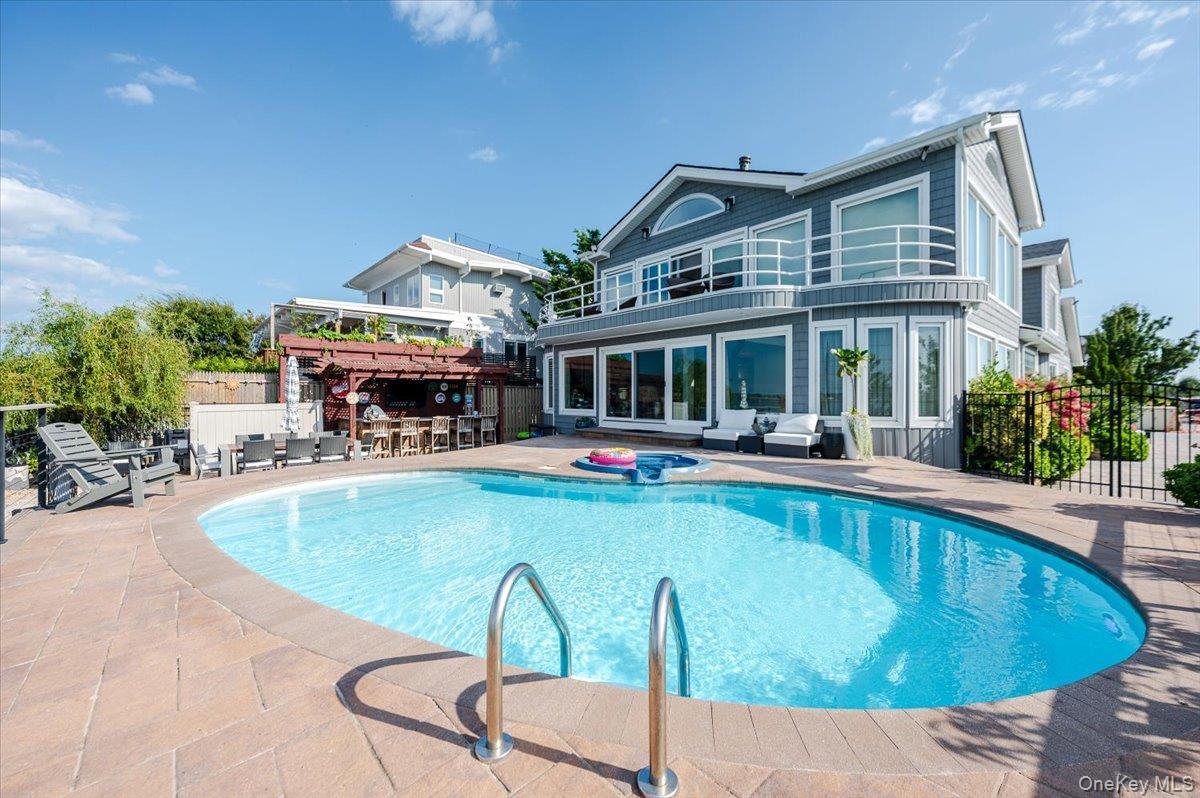 Rear view of house featuring a patio, an in-ground hot tub, and a balcony