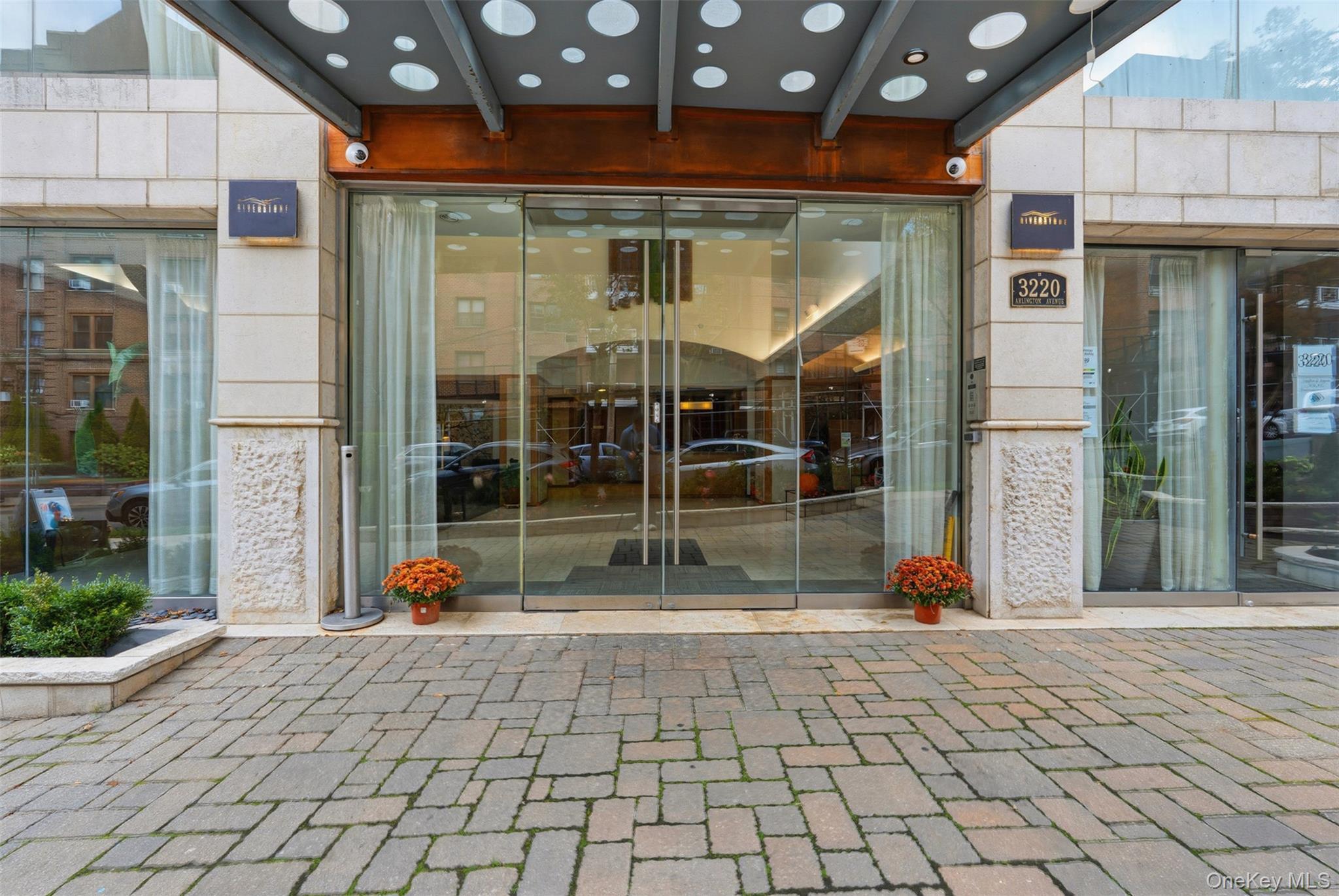 Modern building entrance featuring a stone-clad facade and automatic glass doors