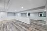 Spacious lower level featuring wood-finish flooring, recessed lighting, and a built-in wet bar with a beverage refrigerator