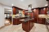 Gourmet kitchen featuring rich wood cabinetry, granite countertops, a tiled backsplash, stainless steel appliances including a built-in oven and range