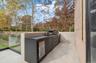 View of patio featuring area for grilling and view of scattered trees