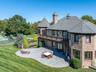 Back of property with brick siding, a chimney, a patio area, a balcony, and a fire pit