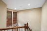 Staircase featuring a rich wood-finish handrail and balusters, two tall windows with horizontal blinds, and recessed ceiling lighting