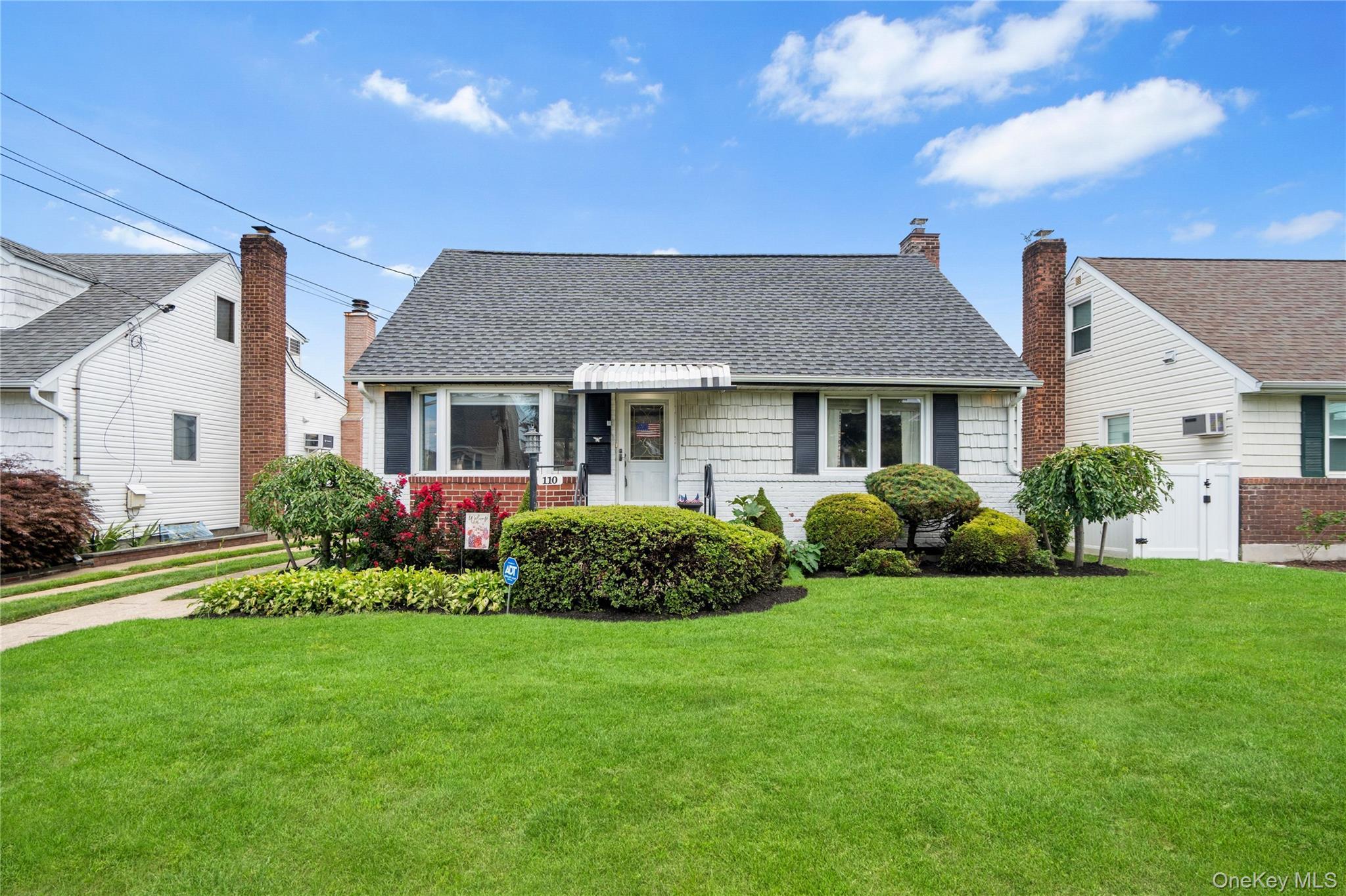 Gable roofline, exterior siding with brick accents, prominent front windows, front entry awning, and established front landscaping