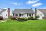 Gable roofline, exterior siding with brick accents, prominent front windows, front entry awning, and established front landscaping