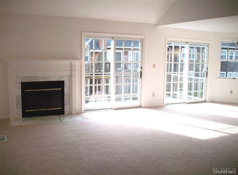 Open concept living room with fireplace and 2 sliding glass doors to balcony.