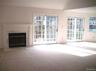 Open concept living room with fireplace and 2 sliding glass doors to balcony.