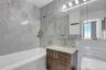 Bathroom with vanity, a combined bath / shower with jetted tub, tile walls, toilet, and backsplash