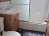 Full bath featuring bath / shower combo with glass door, vanity, and dark marble finish floors