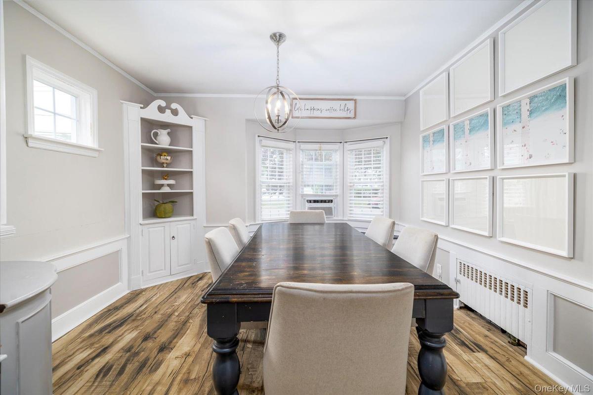 Dining space featuring wood-finish flooring, a built-in corner hutch and a bay window.