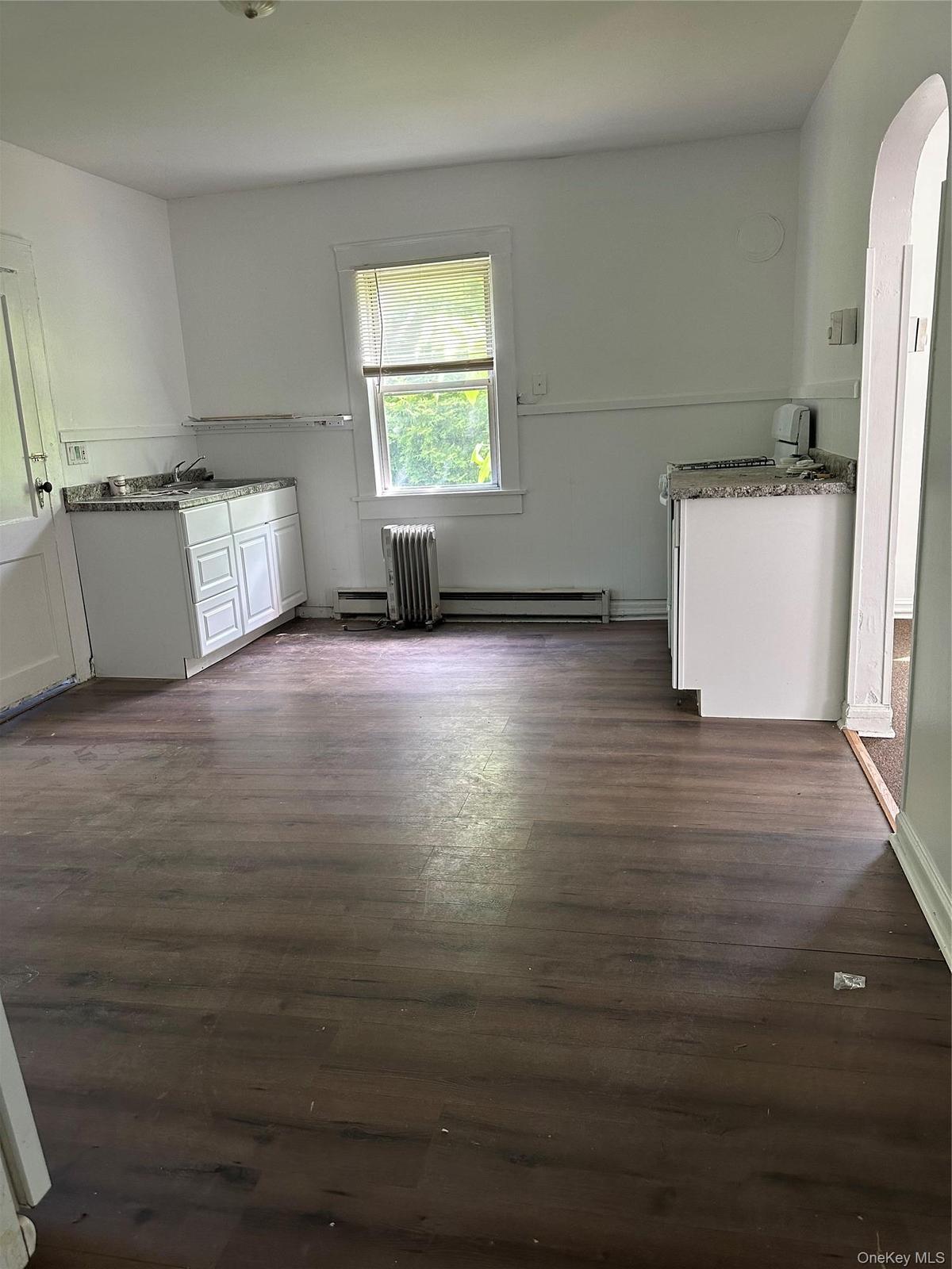 Kitchen with dark hardwood / wood-style flooring and white cabinetry