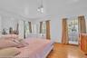 Hardwood flooring throughout featuring white baseboards, two windows with exterior views, and a pair of mirrored sliding closet doors
