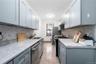 Kitchen featuring gray cabinets, gas range oven, backsplash, stainless steel dishwasher, and light countertops