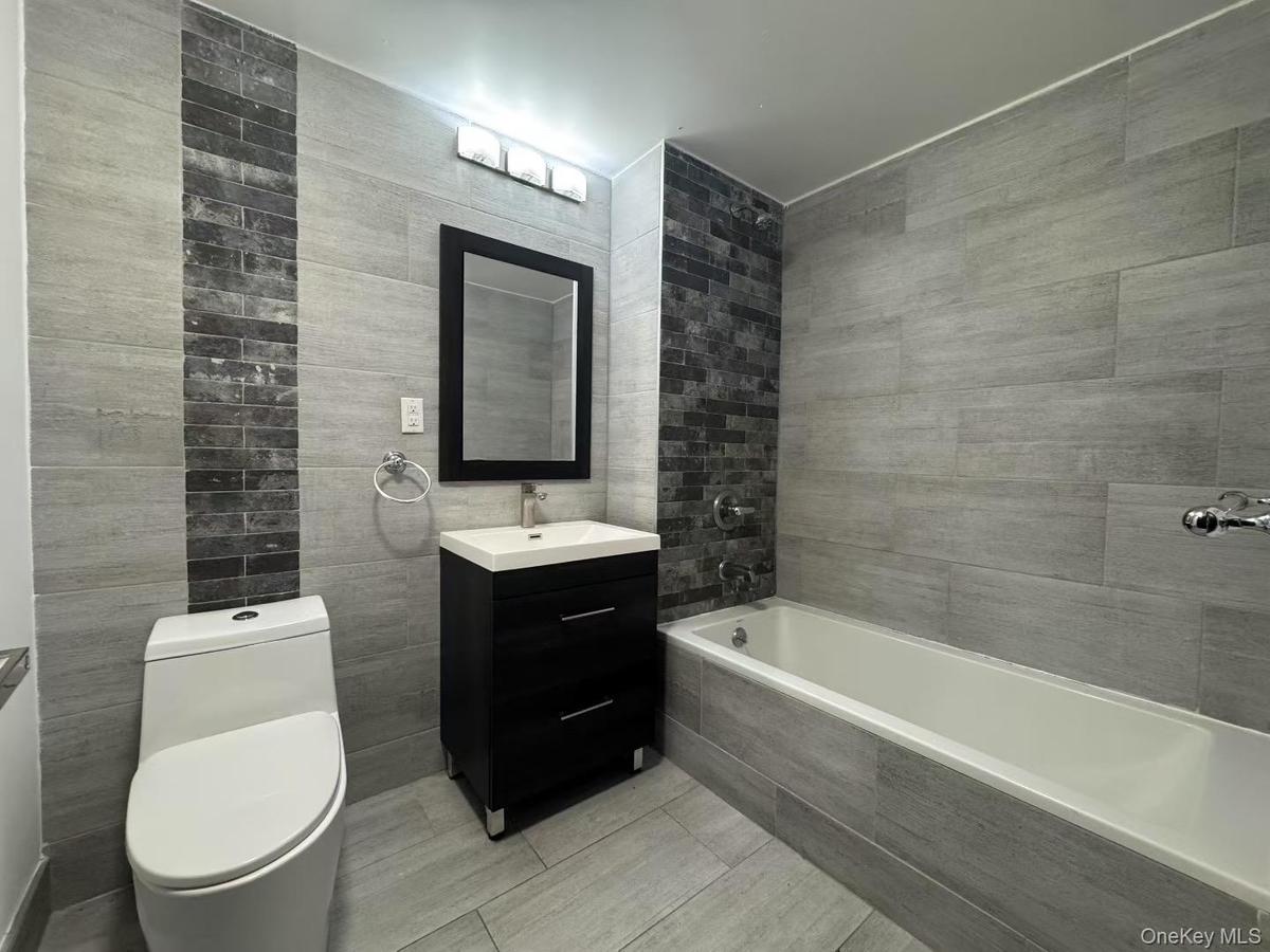 Bathroom featuring vanity, tile walls, and tiled shower / bath