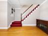 Hardwood flooring with decorative inlay, built-in display niche, fireplace unit, staircase with wood handrail, and crown molding