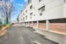 Multi-story building exterior with multiple ground-level garage doors, paved parking area, and a retaining wall