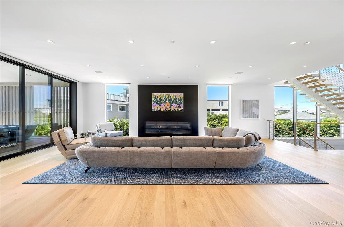 Living area with floor to ceiling windows, wood finished floors, recessed lighting, and stairs