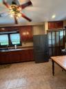 Kitchen featuring tile flooring, wood-finish cabinetry, dark countertop surfaces, and a stainless steel refrigerator.Apt. #1