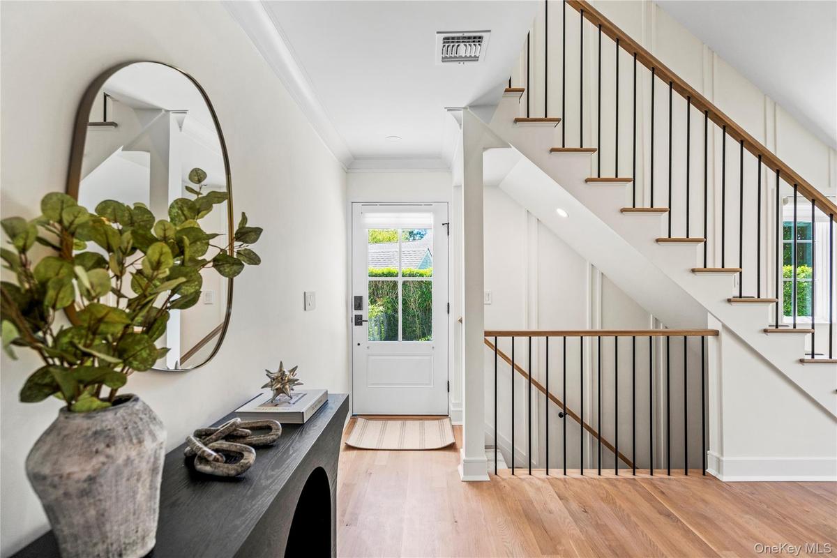 Entryway with ornamental molding, light wood finished floors, and stairs