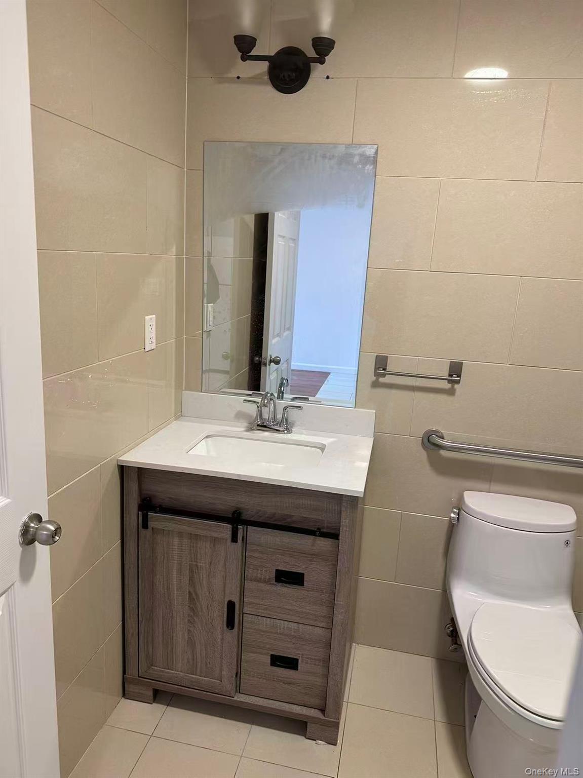 Half bathroom featuring tile walls, vanity, and light tile patterned floors