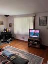 Hardwood-style flooring throughout, complemented by a large window with vertical blinds