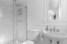 Bathroom with a shower stall, a wainscoted wall, a sink, and toilet