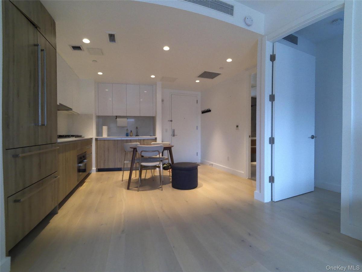 Kitchen featuring modern cabinets, brown cabinetry, light countertops, built in refrigerator, and light wood-style flooring