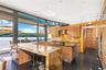 Kitchen with sink, wall chimney exhaust hood, a kitchen island, backsplash, and a water view