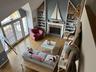 Living room featuring a fireplace, light wood-style floors, high vaulted ceiling, and built in features
