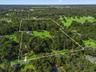 Aerial view of the property highlighting the boundary lines, mature trees, expansive acreage, and private setting.
