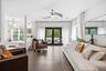 Living area featuring dark wood-finish flooring, a modern ceiling fan, and white walls
