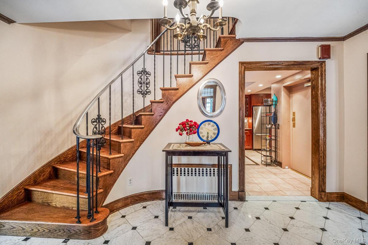 Staircase featuring a chandelier, crown molding, and elevator