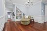 Living area with ornamental molding, a decorative wall, a chandelier, dark wood-style flooring, and a wainscoted wall