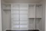 The spacious walk-in closet for Bedroom 2 offers exceptional organization with a custom built-in system featuring multiple open shelves and double han