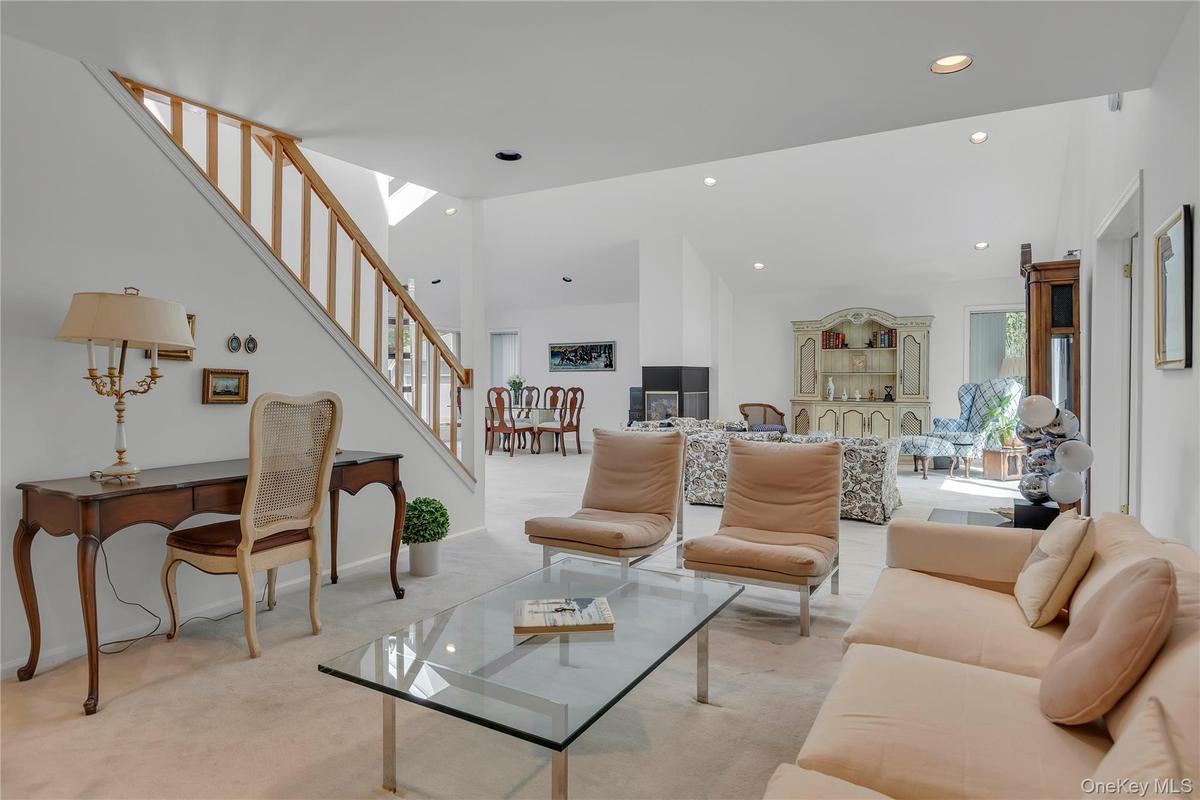 Open-concept living area with vaulted ceilings, recessed lighting, and a wood-finish staircase