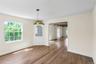 Hardwood flooring extends throughout this room, featuring a built-in corner cabinet with glass paned doors