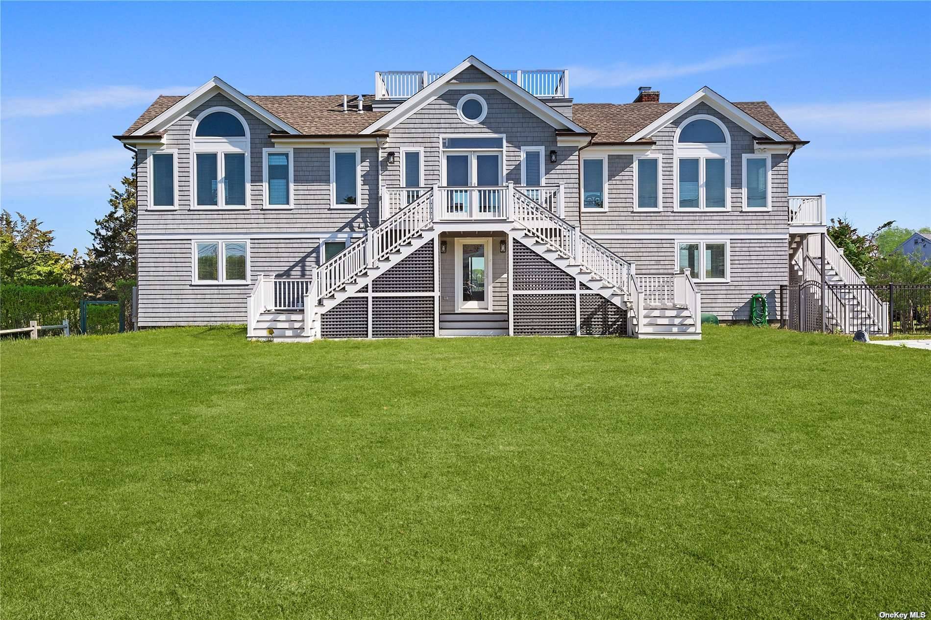 A serene retreat on a full acre with over 120ft of private waterfront in elegant Quogue awaits.