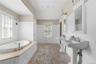 Full bathroom featuring a wainscoted wall, plenty of natural light, tile patterned flooring, a decorative wall, and a garden tub