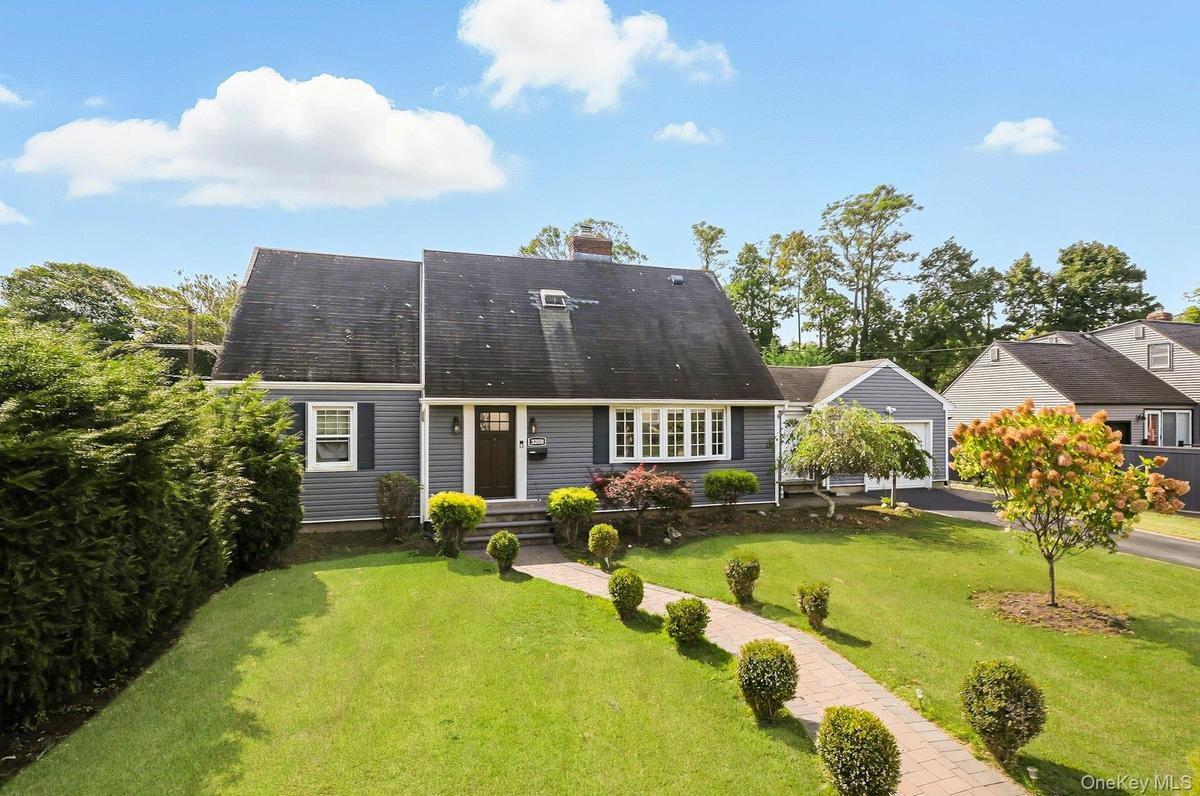 Rear view of house featuring a lawn, a chimney, and a shingled roof