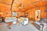 Carpeted living room with wooden walls, wood ceiling, and a ceiling fan