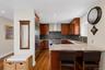 Kitchen featuring wood-finish flooring, custom wood cabinetry, stainless steel appliances, and stone countertops
