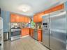 Kitchen featuring appliances with stainless steel finishes, decorative backsplash, light tile patterned flooring, light stone counters, and brown cabi