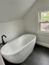 Bathroom featuring lofted ceiling, a soaking tub, and baseboards