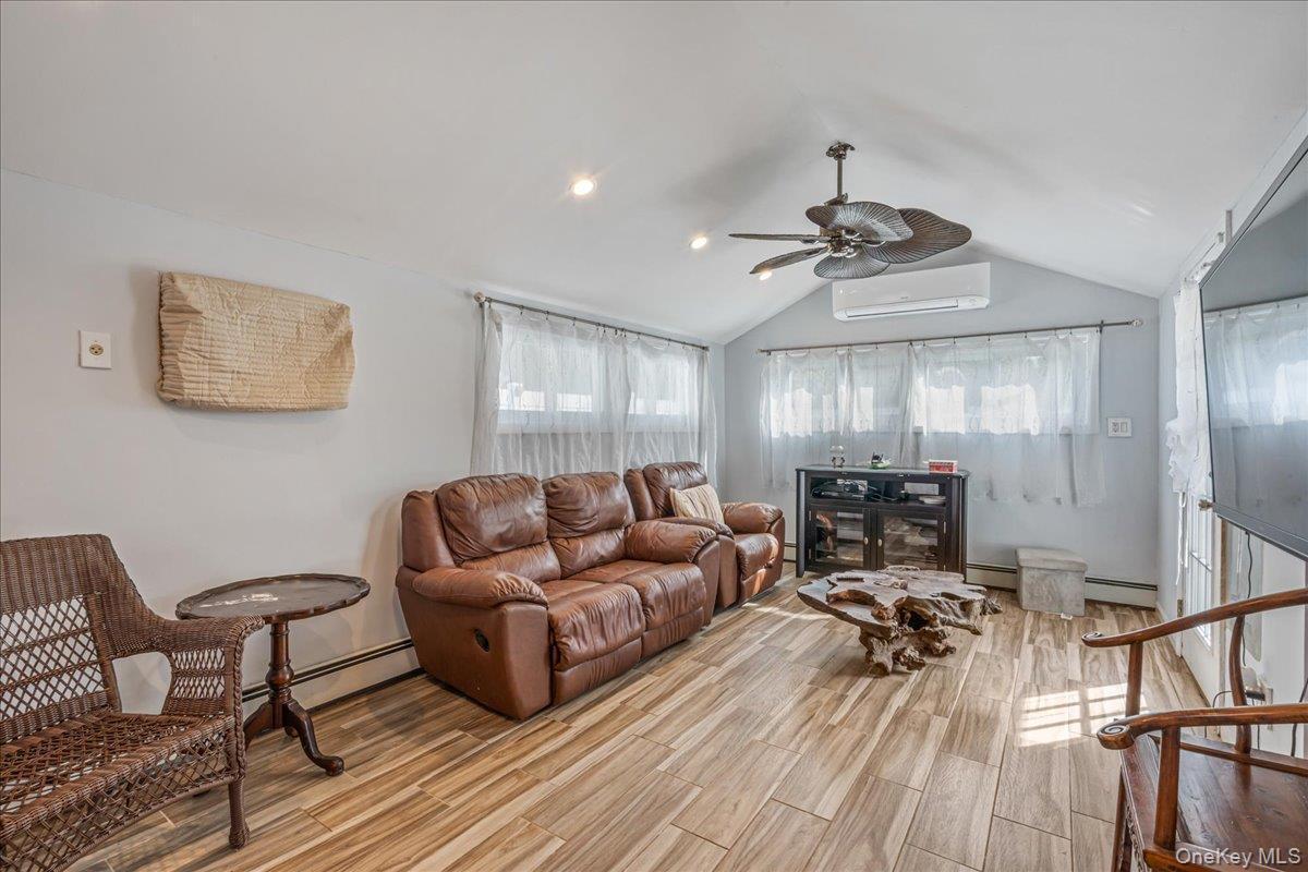 Living area featuring baseboard heating, wood finish floors, and ceiling fan