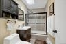 Full bathroom featuring a skylight & dark wood-finish vanity with an integrated white sink.