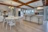Kitchen with tasteful backsplash, wall chimney exhaust hood, white cabinetry, and stainless steel appliances