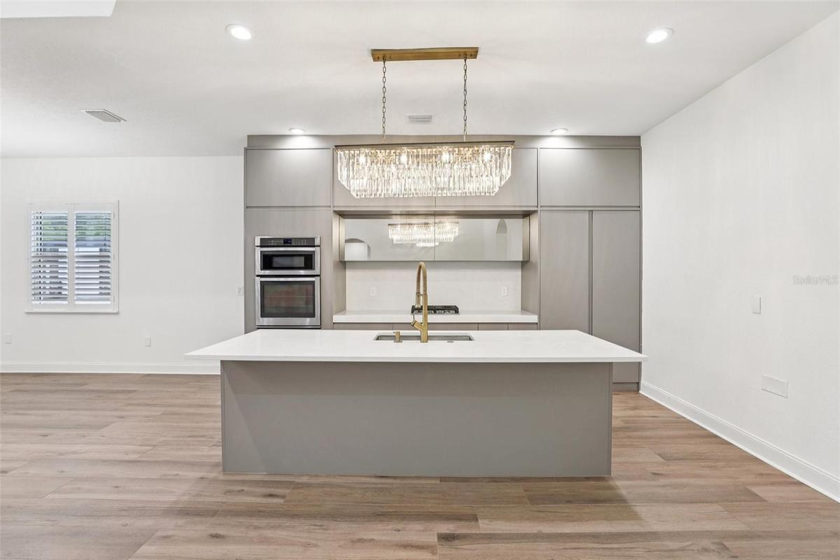 The kitchen is sleek and functional with a LARGE ISLAND for bar seating, upgraded fixtures, and a design that flows effortlessly into the main living