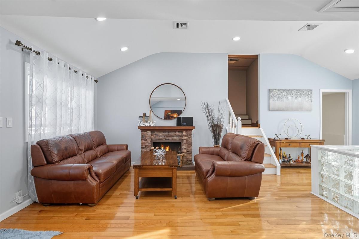 Living area featuring recessed lighting, lofted ceiling, a fireplace, light wood finished floors, and stairway