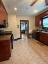 Kitchen featuring wood cabinetry, integrated black appliances, and a tile floor